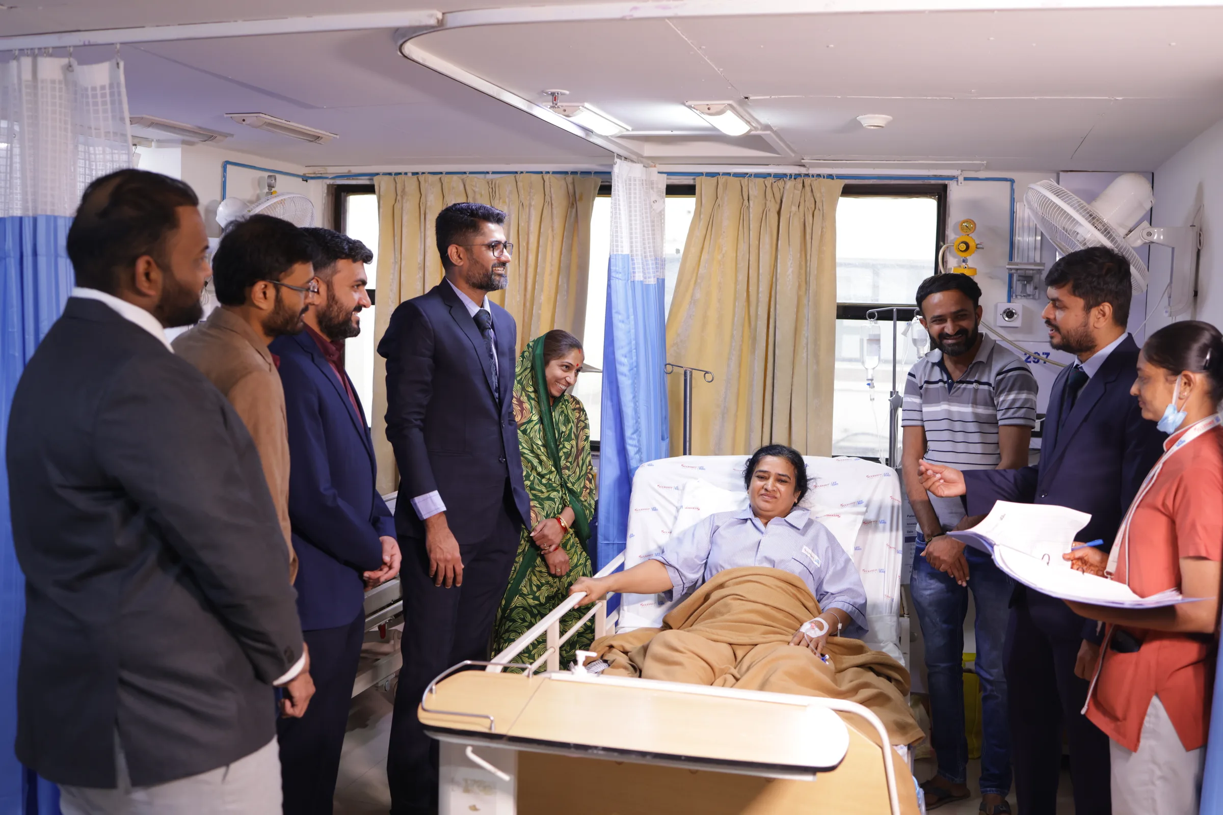 A doctor talking with a patient and their family at the bedside during a ward round.