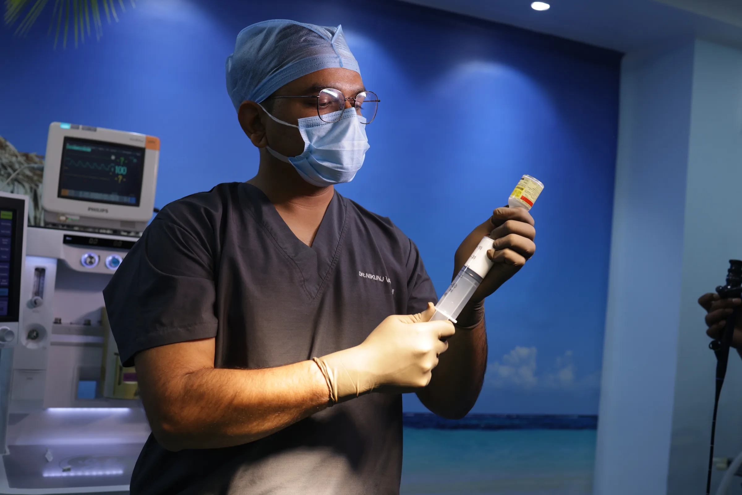 A surgeon preparing medication at the bedside before a case.