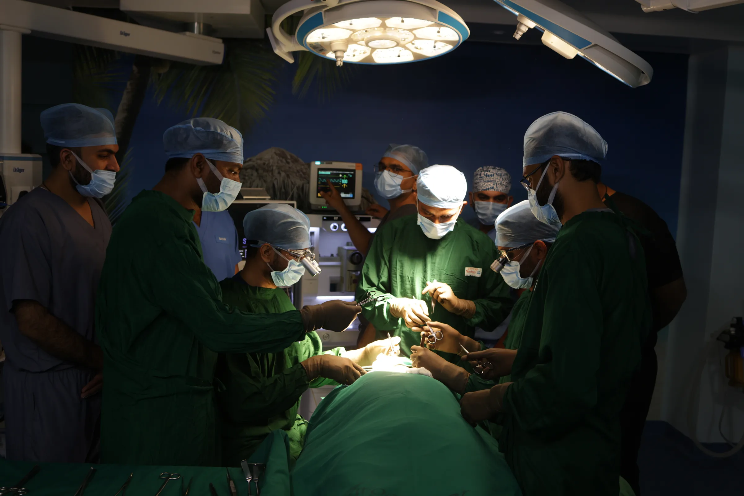 Nine members of the surgical team working round an operating table. The patient is covered by drapes.