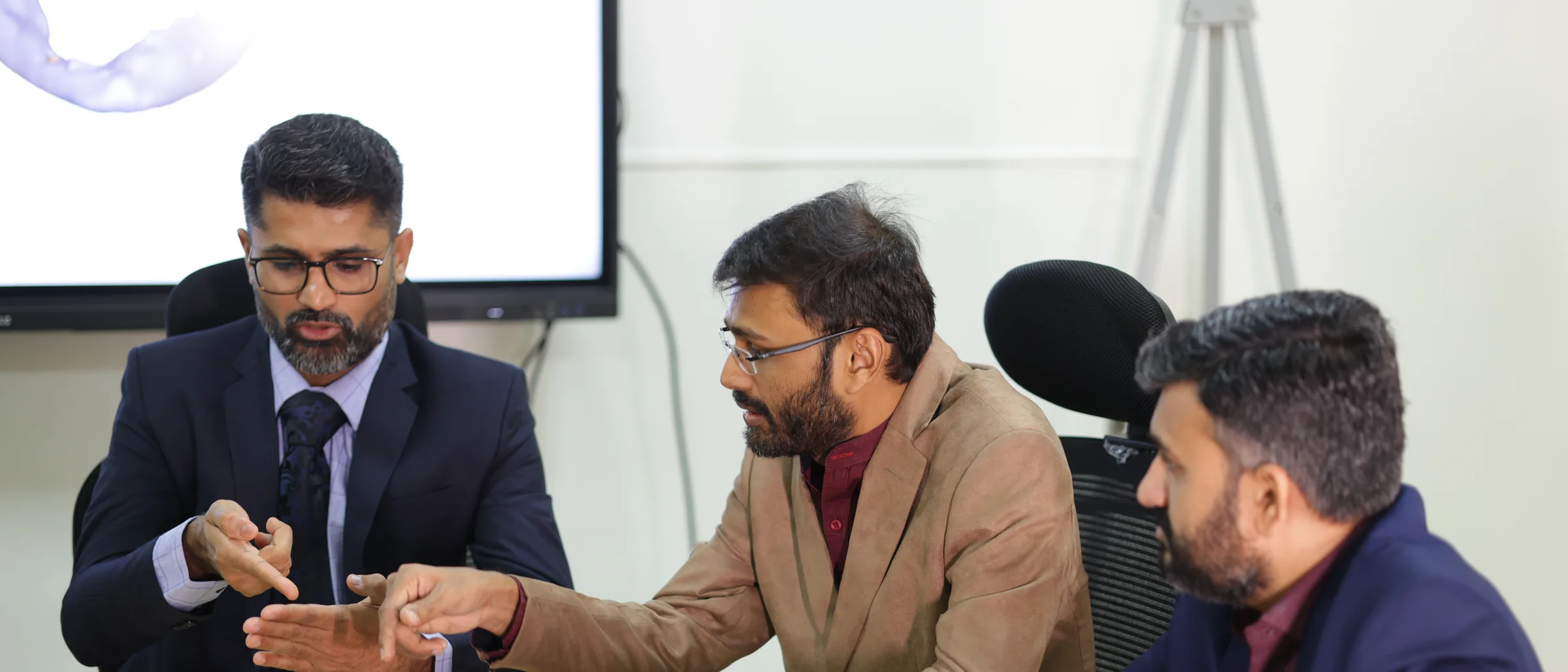 Printed notes and a laptop on the table during a tumour board discussion.