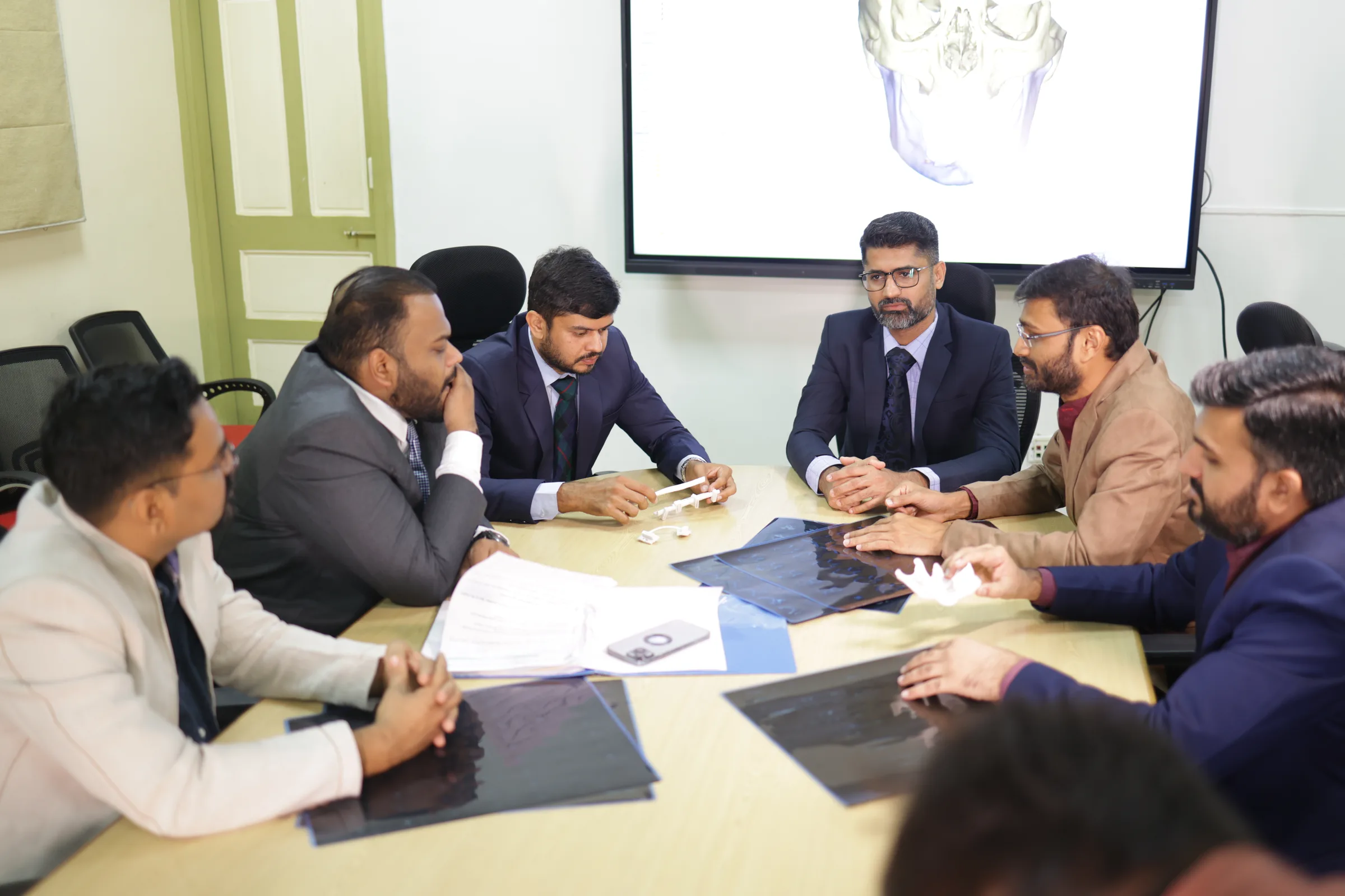 The tumour board meeting: the surgeons seated around the table with a patient's scans spread out in front of them.