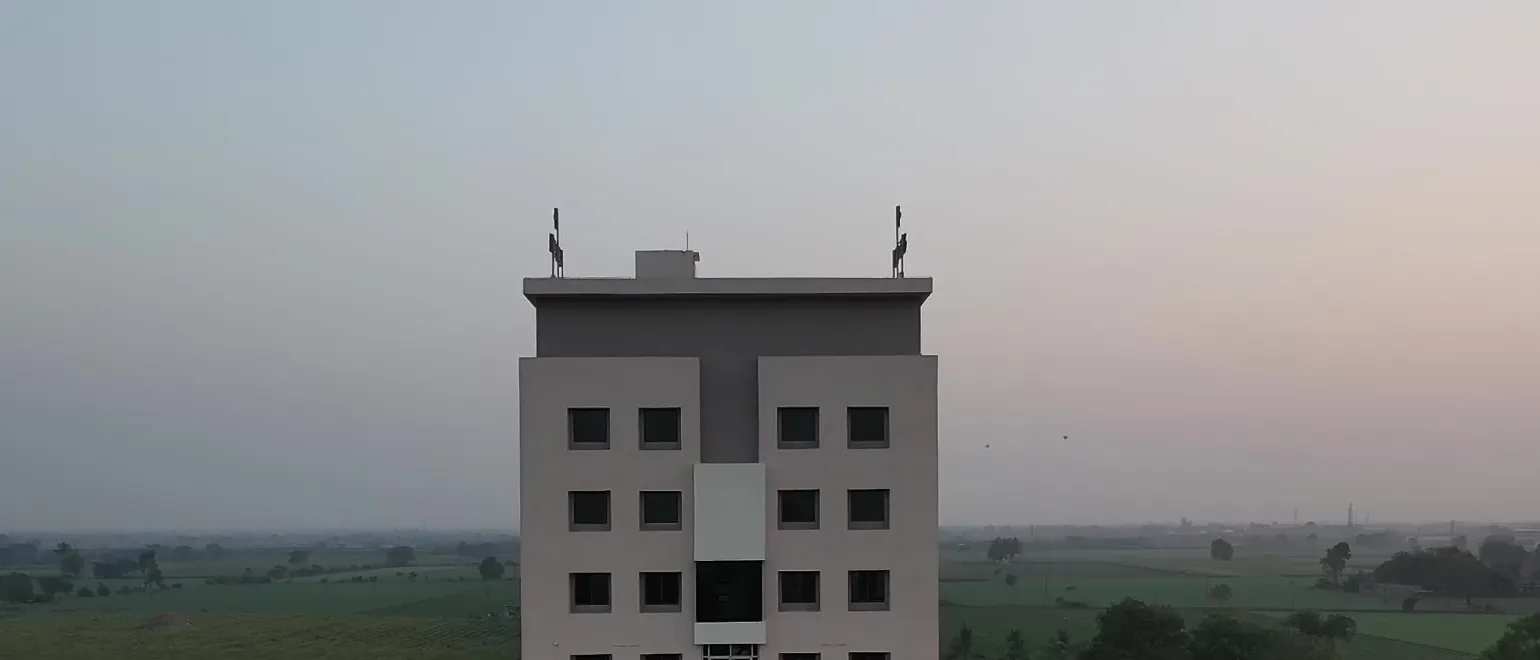 The hospital seen from the air at dusk, standing among green farmland to the horizon.