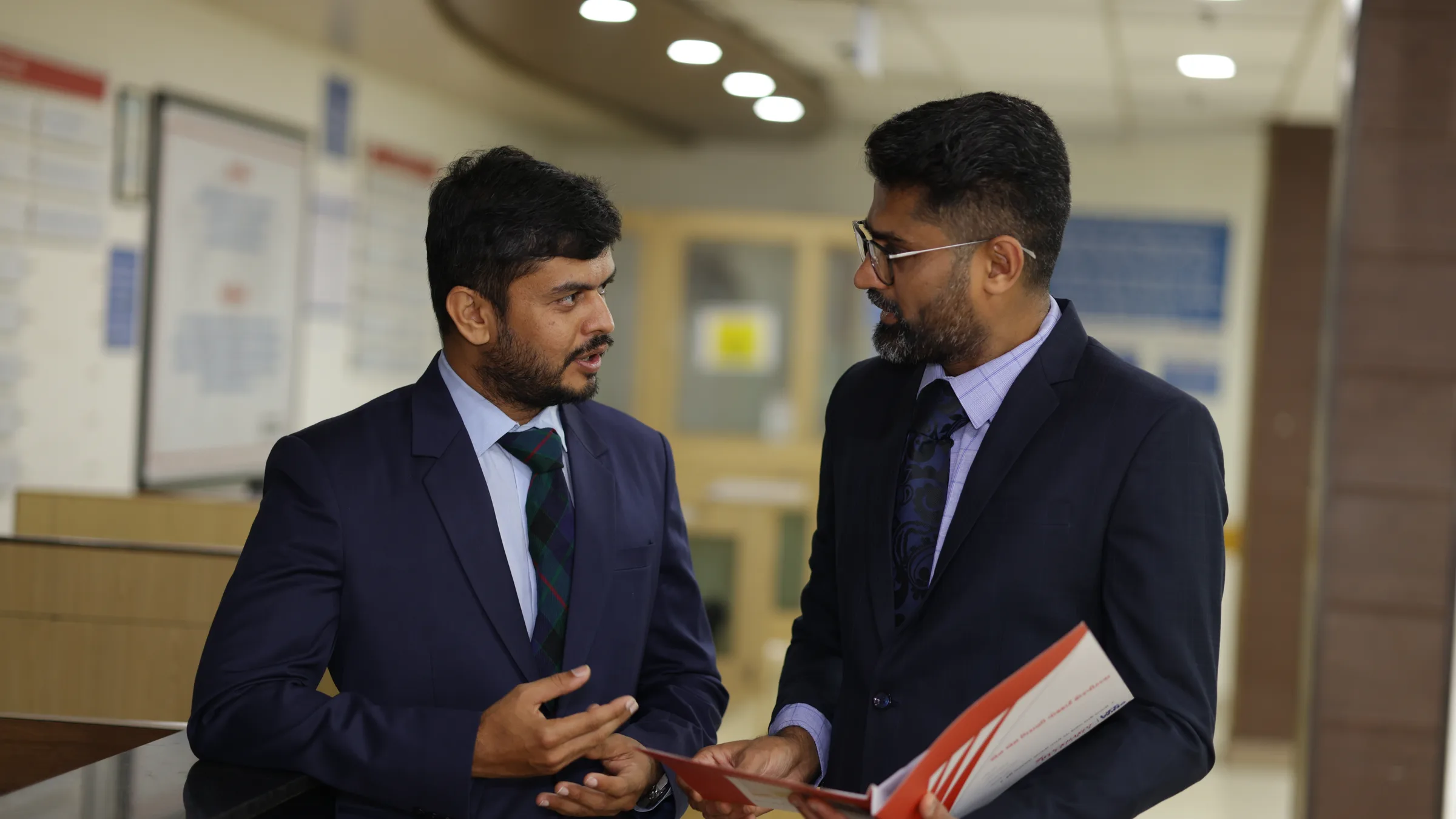 Two of the practice's cancer surgeons standing in the OPD, talking through the same case file.