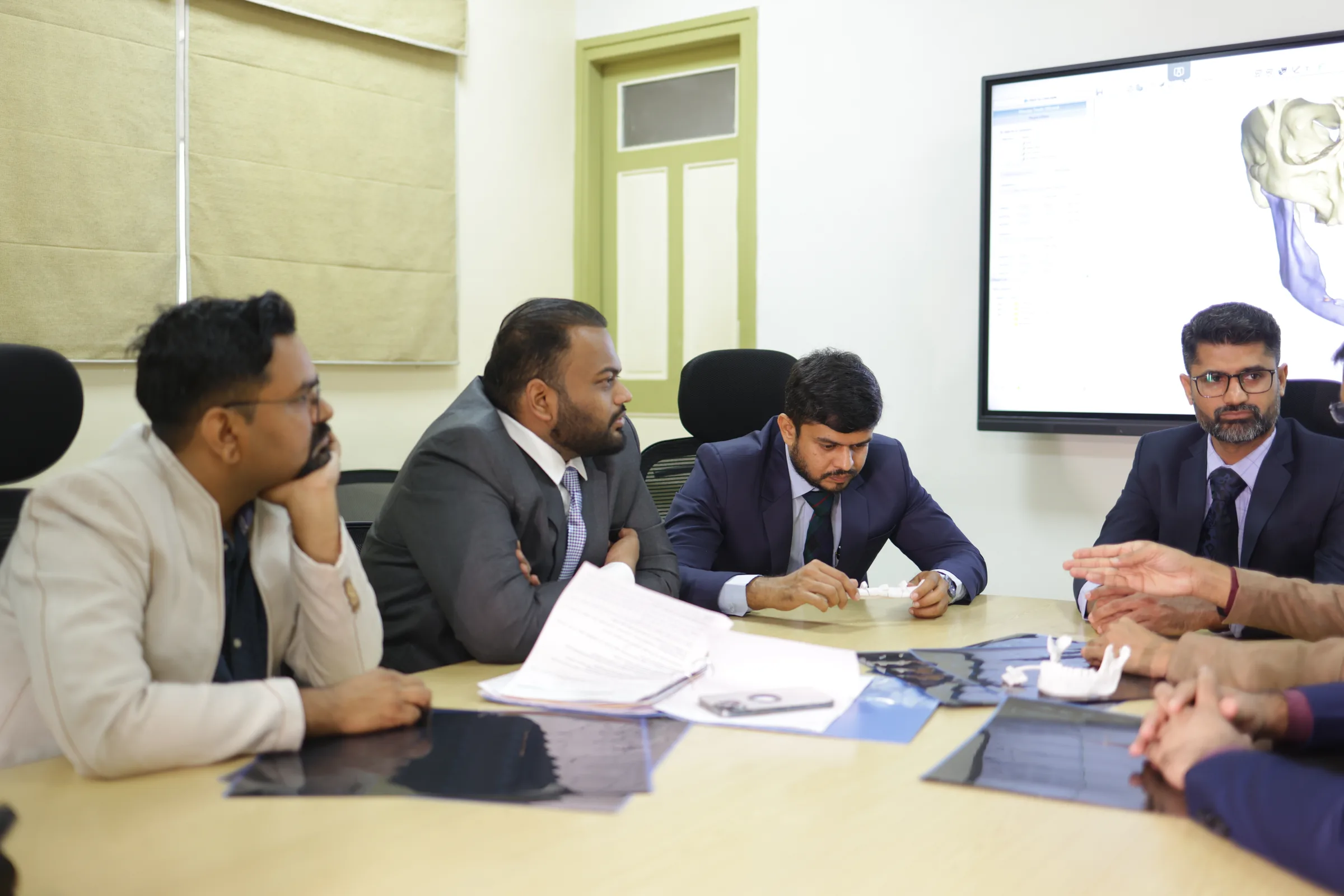 Written notes and papers spread on the tumour board table during a case discussion.